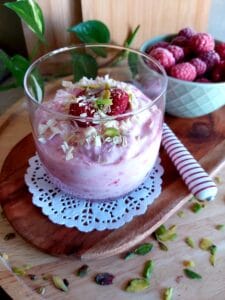 Raspberry Yogurt Dessert in a glass on a wooden platter.