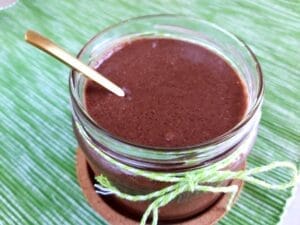 A jar of homemade chocolate spread on a green cloth. 