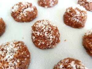 Almond-Coconut-Chocolate Bites on a baking parchment sprinkled with desiccated coconut. 