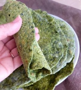 Rolled Spinach Tortilla with more tortillas in the background on a plate.