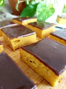 Close-up of sliced Pumpkin Chocolate Cake topped with melted chocolate on a wooden board.