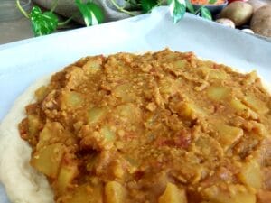 Rolled out pizza dough topped with lentil potato curry. 