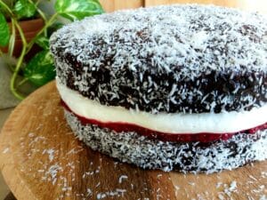 Lamington Cake filled with Mascarpone cream and raspberry filling on a wooden platter. 