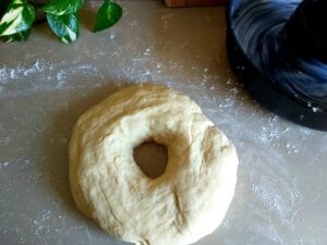 Donut shaped yeast dough on a floured surface.
