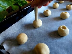 Creating an indent in the centre of each dough ball to be filled with mango curd.