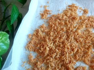 Kataifi coated in butter and honey on a baking tray. 