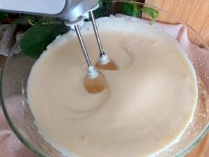 Beating eggs and sugar with an electric mixer until tripled in volume.