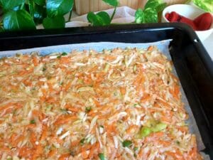 Close-up of a grated vegetable base on a baking tray lined with baking paper.