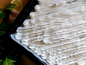 Unbaked pavlova meringue piped diagonally across a baking tray in ridged, even lines.