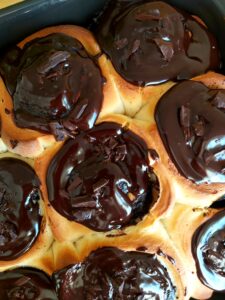 Close-up of golden baked chocolate cinnamon rolls topped with chocolate ganache.