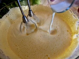 Close-up of pouring milk into the egg yolk mixture.