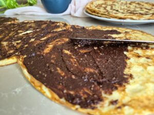 Thin layer of a chocolate-nut filling on golden cooked crêpes.