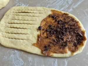 Shaping crescent rolls with decorative scoring pattern.