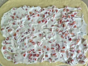 Strawberry–Mint Cheesecake Filling spread on a rolled out dough. 