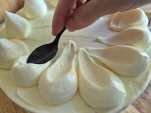 Flattening dollop of diplomat cream with the back of a spoon to create a soft decorative border.