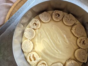 Slices of almond streusel spirals arranged on cake batter, forming a ring.