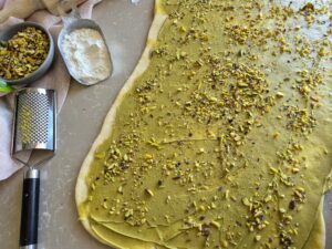 Rolled out dough covered with filling and topped with sliced pistachios. 