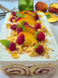 Close-up of Melba Spiral Cake topped with fresh peaches and raspberries.