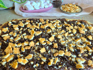 Rolled out dough topped with chocolate filling and crushed graham crackers for S’mores Sweet Rolls.