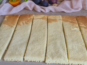 Vanilla sponge base cut into even strips for Fig Pistachio Honey Rolled Layer Cake 