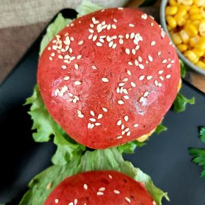 Close-up of dragon fruit burger buns filled with vegetable and lettuce leaves.