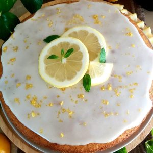 Lemon cake garnished with a lemon glaze, lemon slices, and mint leaves.