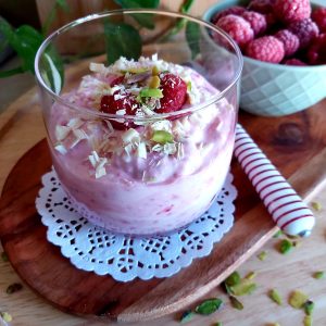 Raspberry Yogurt Dessert in a glass on a wooden platter.