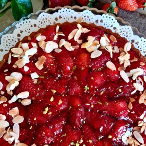 Strawberry Cake topped with chopped pistachios and garnished with sliced almonds