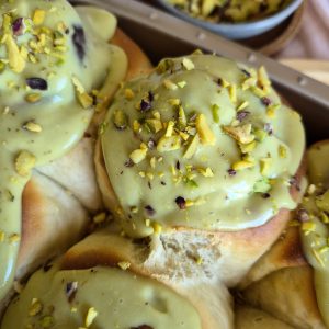 Close-up of golden baked Pistachio Lemon Rolls topped with pistachio cream and sliced pistachios.