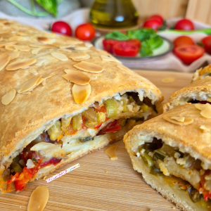 Golden baked and sliced Summer Veggie Roll with roasted vegetables in the background.