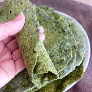 Rolled Spinach Tortilla with more tortillas in the background on a plate.